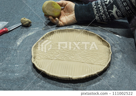Plate of handmade light clay on a potter's table in a pottery workshop. Close up 111002522