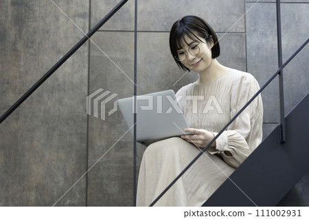 一位戴眼鏡的女士在樓梯上使用筆記型電腦 111002931
