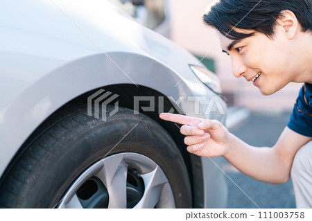 Young man checking tire pressure Young man checking tire pressure 111003758
