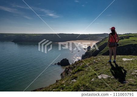 Young Woman Looks Over Atlantic Coast And Barafundle Bay Beach In Wales, Pembrokeshire, United Kingdom 111003791