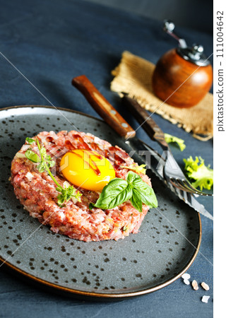 Top view of raw minced meat with liquid egg yolk for preparation of meatball placed on gray plate Top view of raw minced meat with liquid egg yolk for preparation of meatball placed on gray plate 111004642