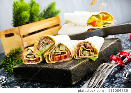 Salmon and cream cheese wraps. Rolls with smoked salmon, basil and rocket salad. Burrito on serving board 111004886