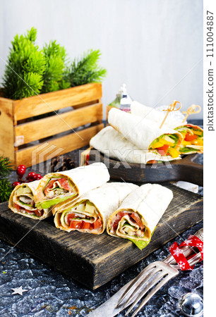 Salmon and cream cheese wraps. Rolls with smoked salmon, basil and rocket salad. Burrito on serving board 111004887