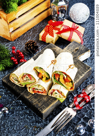 Salmon and cream cheese wraps. Rolls with smoked salmon, basil and rocket salad. Burrito on serving board Salmon and cream cheese wraps. Rolls with smoked salmon, basil and rocket salad. Burrito on serving board 111004889