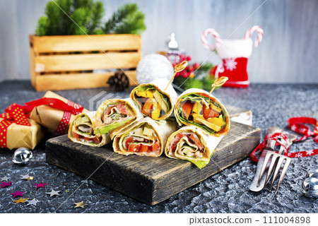 Salmon and cream cheese wraps. Rolls with smoked salmon, basil and rocket salad. Burrito on serving board 111004898