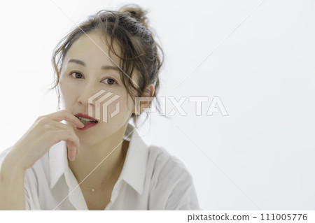 Portrait of a woman holding her finger in her mouth Portrait of a woman holding her finger in her mouth 111005776