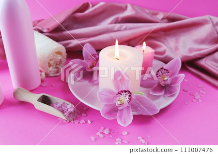 Spa still life with orchid flowers and candles on pink background, relaxation atmosphere, body care  111007476