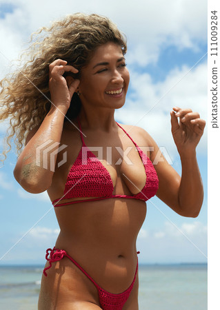 Beautiful happy woman on the beach. Smiling girl in Bikini near sea 111009284