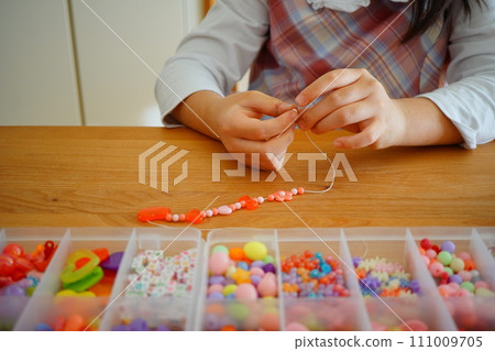 A 4th grade elementary school girl is enjoying playing with beads at home. A 4th grade elementary school girl is enjoying playing with beads at home. 111009705