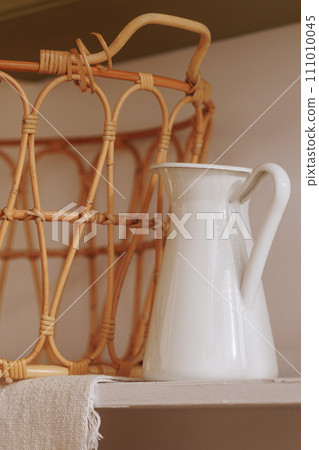 White enamel jug beside woven basket 111010045