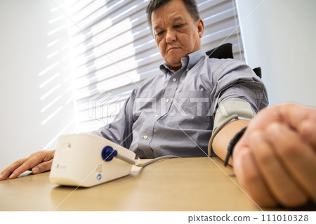 Asian man in 50s checking blood pressure with instrument in the work office 111010328
