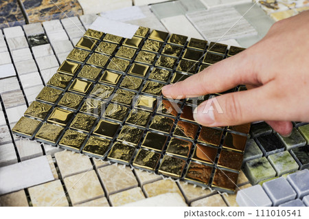 designer's hand choosing samples of interior stone material consists concrete tiles, quartz stones, artificial stones, graphic tile. 111010541