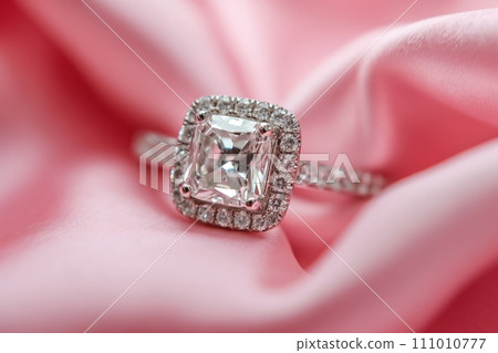 Diamond engagement ring on a pink silk background. Luxury female jewelry close-up 111010777