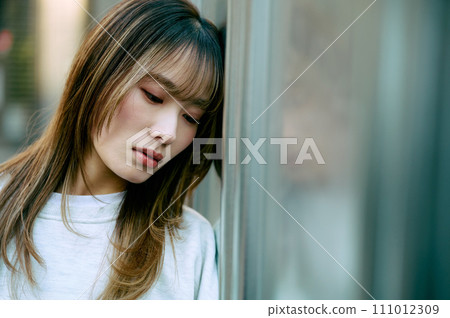 A young woman leaning against the wall 111012309