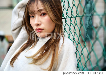 靠在鐵絲網上的年輕女子 靠在鐵絲網上的年輕女子 111012341