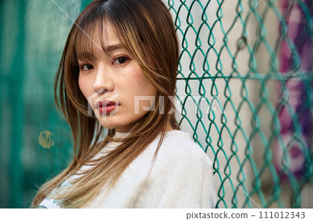 靠在鐵絲網上的年輕女子 靠在鐵絲網上的年輕女子 111012343