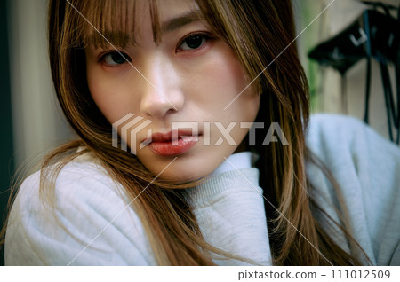 Young woman leaning on wire mesh 111012509