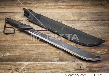 bush clearing machete with carbon steel blade and saw against rustic wooden deck bush clearing machete with carbon steel blade and saw against rustic wooden deck 111012583