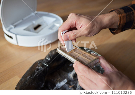 Cleaning the filter of the vacuum robot cleaner from dirt, close-up. 111013286