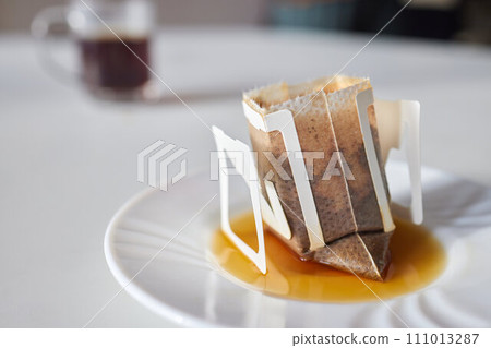 brewing process,a bag filled with boiling water for drip coffee in a cup,top view. brewing process,a bag filled with boiling water for drip coffee in a cup,top view. 111013287
