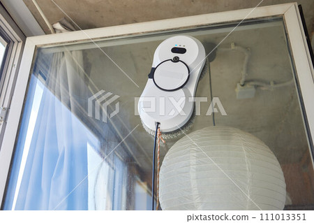 A window cleaner robot washes glass against the backdrop of multi-storey buildings. 111013351