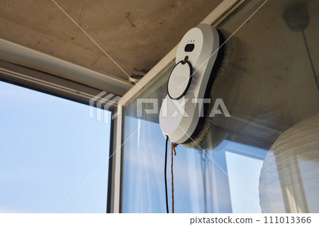 A window cleaner robot washes glass against the backdrop of multi-storey buildings. 111013366