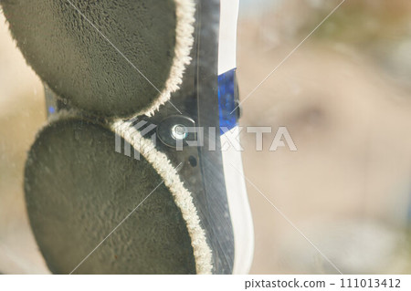 A window cleaner robot washes glass against the backdrop of multi-storey buildings. 111013412