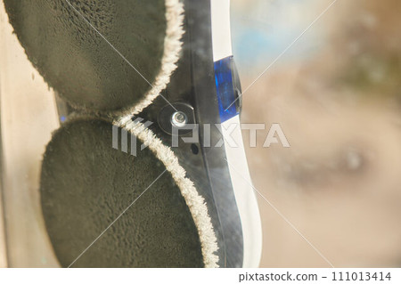 A window cleaner robot washes glass against the backdrop of multi-storey buildings. 111013414