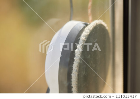 A window cleaner robot washes glass against the backdrop of multi-storey buildings. 111013417