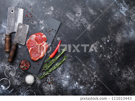Raw Rib eye fillet on stone board with meat cleaver hatchets with salt and pepper with rosemary Raw Rib eye fillet on stone board with meat cleaver hatchets with salt and pepper with rosemary 111013443
