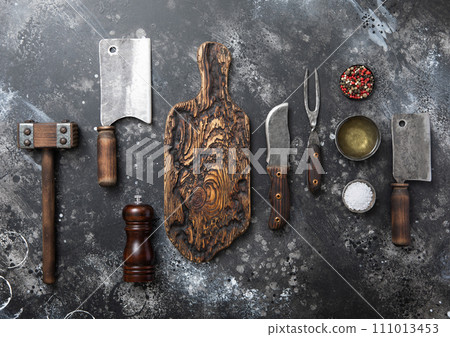 Kitchen meat utensils set on dark kitchen background. Meat cleaver,fork,knife Kitchen meat utensils set on dark kitchen background. Meat cleaver,fork,knife 111013453