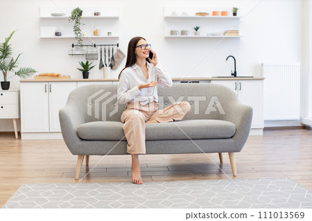 Woman relaxing on sofa and using modern smartphone for talking with family. Woman relaxing on sofa and using modern smartphone for talking with family. 111013569