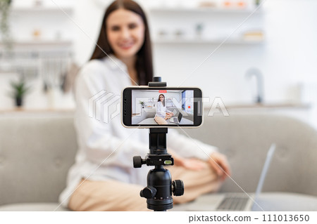 Demanding tutor using modern smartphone with tripod for online training. Demanding tutor using modern smartphone with tripod for online training. 111013650
