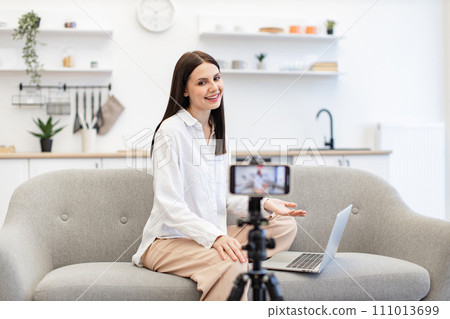 Cheerful content maker recording video to followers on modern smartphone. Cheerful content maker recording video to followers on modern smartphone. 111013699