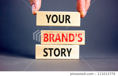 Branding and your brand story symbol. Concept words Your brands story on beautiful wooden blocks. Beautiful grey background. Businessman hand. Business branding your brand story concept. Copy space. 111013778