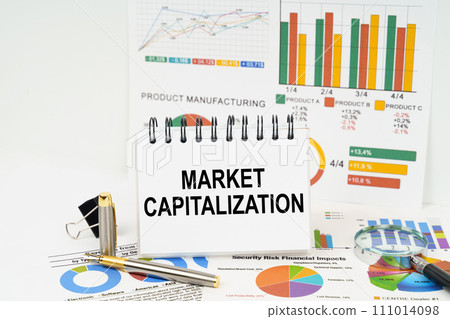 On the table are reports with graphs and a notepad with the inscription - Market capitalization 111014098