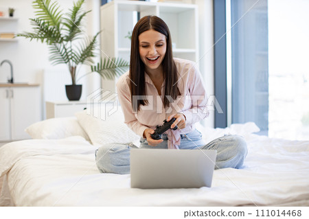 Caucasian brunette using modern devices enjoying favorite video game on weekend. Caucasian brunette using modern devices enjoying favorite video game on weekend. 111014468