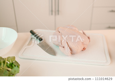Chicken meal cooking concept. Female hands cutting chicken breast meat on kitchen tables background with bowls , oil , soy sauce and ingredients, top view Chicken meal cooking concept. Female hands cutting chicken breast meat on kitchen tables background with bowls , oil , soy sauce and ingredients, top view 111014629