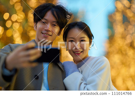 A man and a woman take a commemorative photo at a night view illuminated by illuminations 111014766