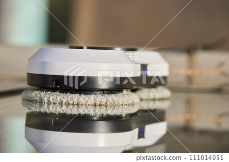 A window cleaner robot washes glass against the backdrop of multi-storey buildings. 111014951