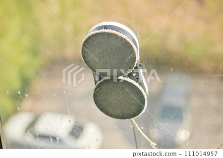 A window cleaner robot washes glass against the backdrop of multi-storey buildings. 111014957