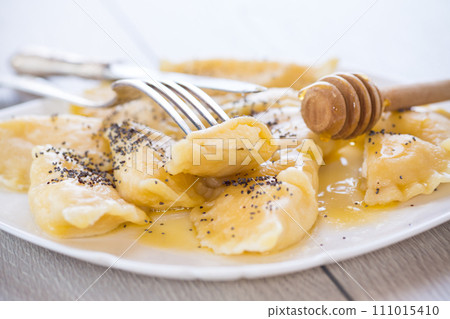 sweet cooked dumplings with cottage cheese, poppy seeds and honey. 111015410