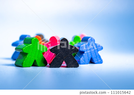 A varied collection of wooden figures in different colors, arranged in a seated position next to one another. 111015642