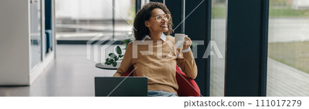 Smiling business woman in eyeglasses have a coffee break during working on laptop in cozy cafe 111017279