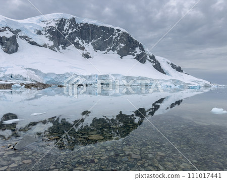 A huge high breakaway glacier in the southern ocean off the coast of Antarctica, the Antarctic Peninsula, the Southern Arctic Circle, azure water, cloudy weather 111017441