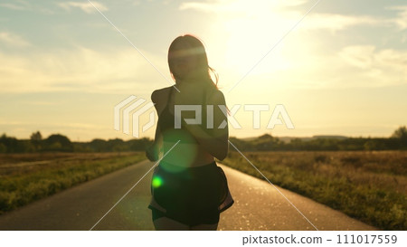 silhouette sports girl running along road sunset, running sportswear, motivation victory. sport running with concentration, fitness man checking result. beautiful woman tracksuit, stretching body 111017559