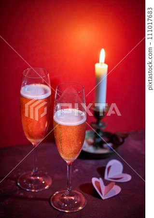 two glasses of champagne and a burning candle two glasses of champagne and a burning candle 111017683