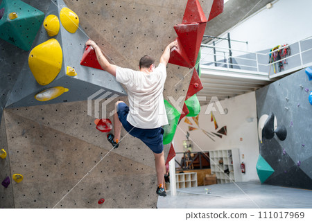 Determined man climbing artificial wall in sports 111017969