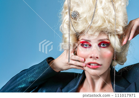 Funny woman wearing wig and makeup in blue studio Funny woman wearing wig and makeup in blue studio 111017971