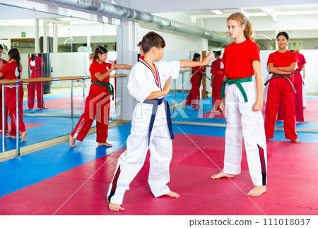 Young girls and boys sparring during karate training 111018037